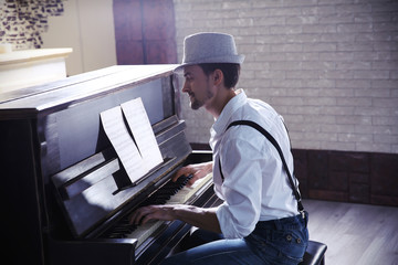Naklejka na ściany i meble Handsome young man in hat making piano music