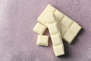 White chocolate pieces on color wooden background
