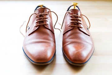Brown leather shoes with wood shoe forms on wooden table