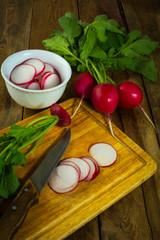 Bunch of fresh radish and salad on the old wood cutting board, vertical    