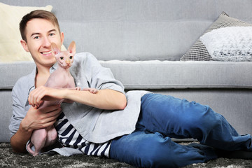 Young handsome man lies with cat on floor at home