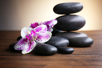 Obraz na płótnie Canvas Black pebbles with orchid on wooden table
