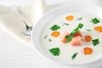 Delicious cream soup with salmon and carrot in white bowl