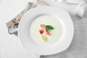 Delicious cream soup with fish and sliced lemon on white table in the restaurant