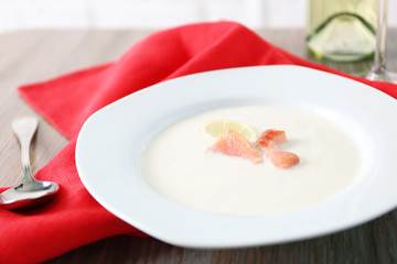 Tasty salmon cream soup with wine and red cotton serviette on wooden table, close up