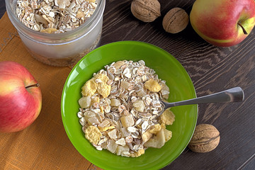 Muesli.  Muesli in a green plate and in a glass jar on a napkin on a dark wooden background.
 