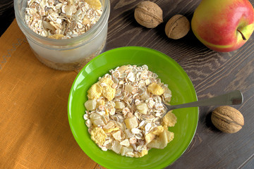 Muesli.  Muesli in a green plate and in a glass jar on a napkin on a dark wooden background.
 