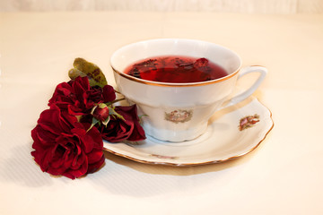 Cup of hibiscus tea with roses on white background 