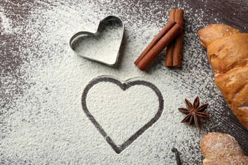 Heart of flour, croissant and spices on gray background