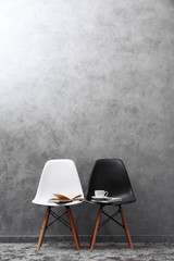 Stylish conception with white and black chairs on grey background
