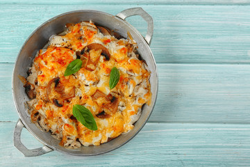 Roasted mushrooms, chicken and cheese gratin in pan, on wooden background