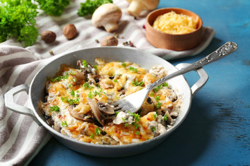 Roasted mushrooms, chicken and cheese gratin in pan, on color wooden background