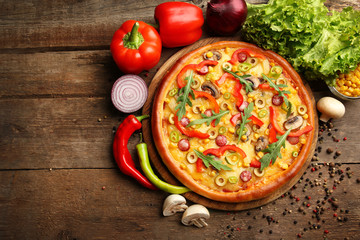 Delicious pizza with vegetables on wooden background
