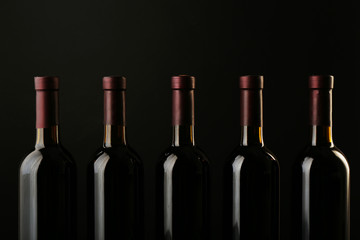 Wine bottles in a row on black  background, close up