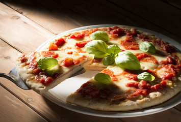 Pizza with tomatoes mozzarella and basil on the wooden table