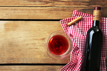 Bottle of wine with a corkscrew on wooden background