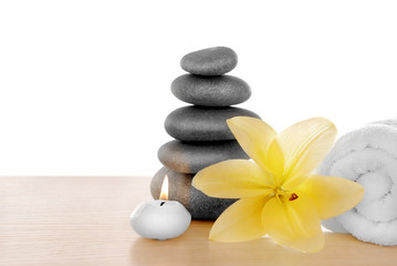 Fototapeta na wymiar Spa stones with candle, towel and lily, isolated on white