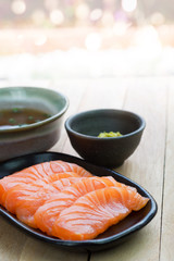 Sliced raw salmon on black plate with abstract background