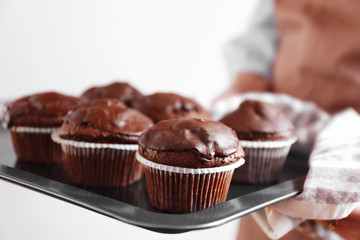 Housewife holding oven-tray with chocolate cupcakes, close up