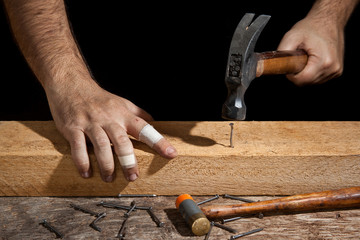 A craftsman hammering bent nail with difficulty - obrazy, fototapety, plakaty