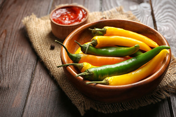 Chili peppers, homemade hot sauce and spices on sackcloth, on wooden background