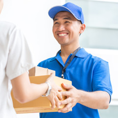 Woman accepting a delivery of cardboard boxes from deliveryman