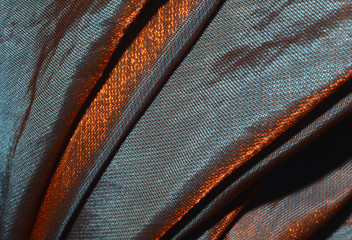 Iridescent fabric chameleon in orange, brown and purple colors, texture, background