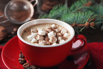 Mug of hot chocolate with marshmallows, fir tree branch on wooden background