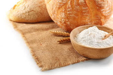 Bread bread with ears and flour on napkin isolated on white