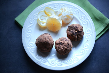 Chocolate balls with lemon on plate on dark blue background