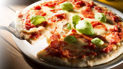 Pizza with tomatoes mozzarella and basil on the wooden table