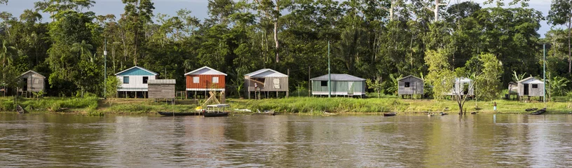 Fotobehang Houten huis op palen langs de Amazone-rivier en het regenwoud, B © piccaya