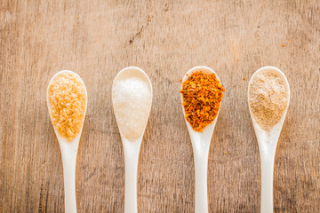 Condiments in spoon and on old table