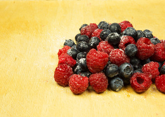 A handful of frosted highbush blueberries and raspberries on old