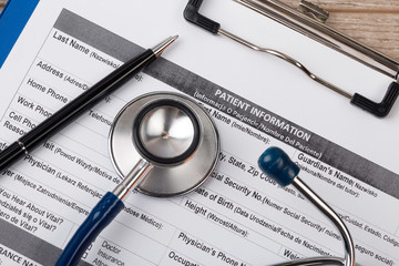 Stethoscope and pen laying on patient information blank