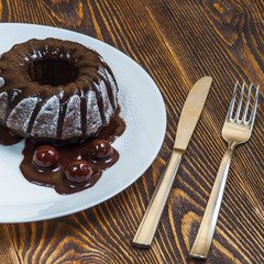 Chocolate cake, glazed cherry, fork and knife