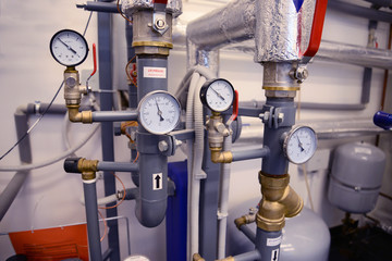 Close up of pipes, valves and manometer of heating system