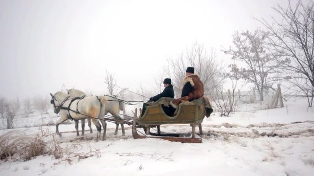 Old father and his son having a ride in sledge pulled by horses 