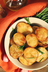Delicious baked potato with rosemary in bowl on table close up