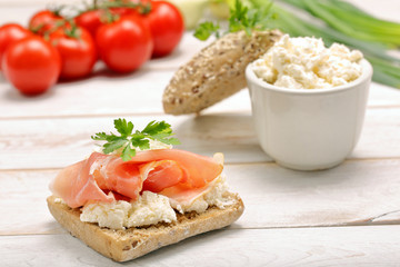 Sandwich with white cottage cheese and ham on white wooden backg