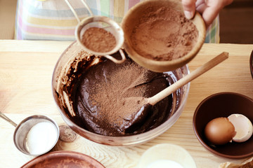 Woman preparing dough for chocolate pie on table close up