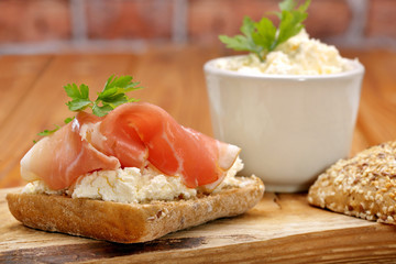 Sandwich with white cottage cheese and ham on wooden background