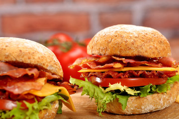 Bacon burgers with tomato and cheese on wooden table