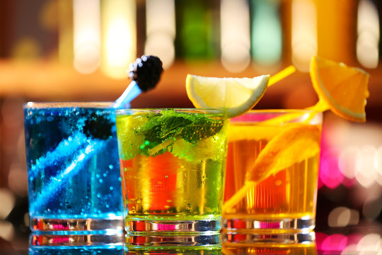 Glasses of cocktails on bar background
