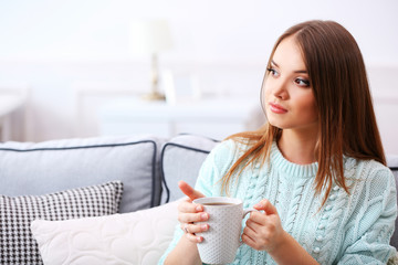 Pretty young woman drinking tea at home