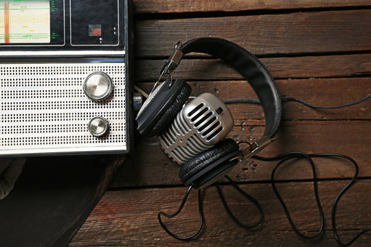 Radio with headphones and microphone on wooden background