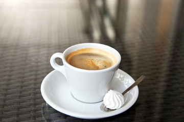 Cup of tasty coffee, zephyr and spoon in cafe