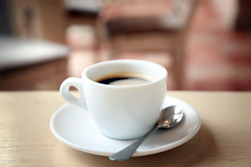 Cup of tasty coffee with spoon in cafe