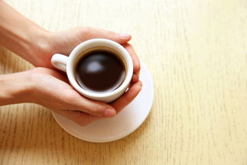 Cup of coffee with hands on table background
