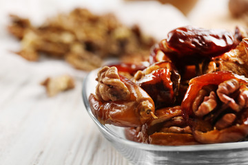 Walnut and date fruit in plate on wooden table, close-up